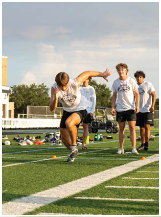 A group of people are standing on a football field. Description generated by AI