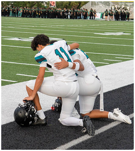 Two football players hugging on the field. Description generated by AI