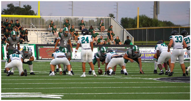 A football field with a group of football players in green and white uniforms. Description generated by AI