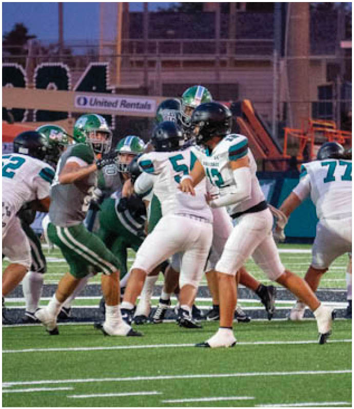 A football game is taking place on a field with players wearing green and white uniforms. Description generated by AI