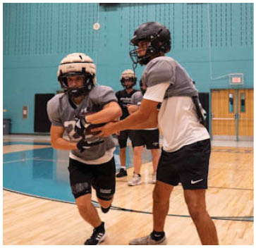 A group of young men playing football in a gym. Description generated by AI