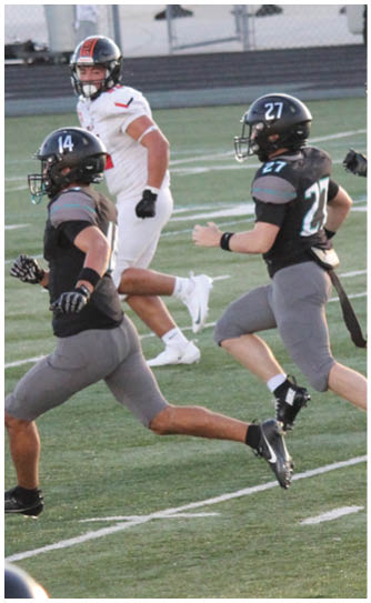 A group of football players running on a field. Description generated by AI