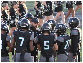 A group of football players wearing black and grey uniforms. Description generated by AI