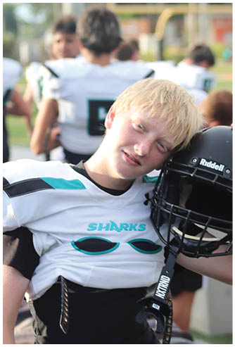 A young boy wearing a football helmet. Description generated by AI