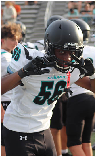 A football player wearing a black and white jersey with the number 55 on it. Description generated by AI