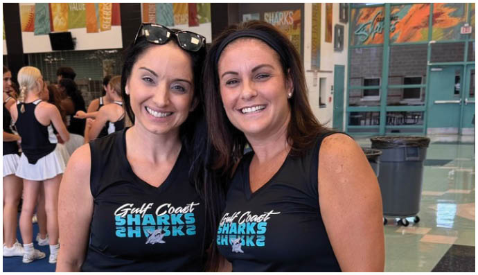 Two women wearing black shirts and blue gloves. Description generated by AI
