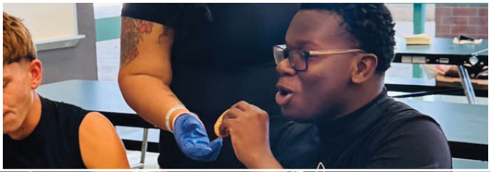 A woman wearing a black shirt and blue gloves is serving food to a man. Description generated by AI