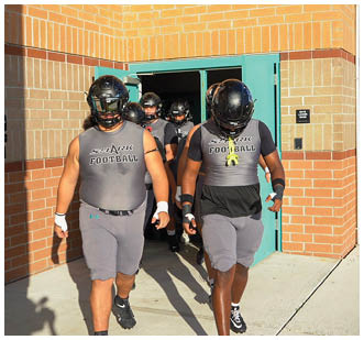Three men wearing grey uniforms and helmets. Description generated by AI
