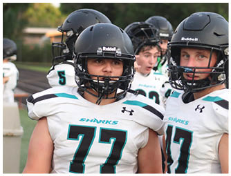 Two football players wearing black helmets and white jerseys. Description generated by AI