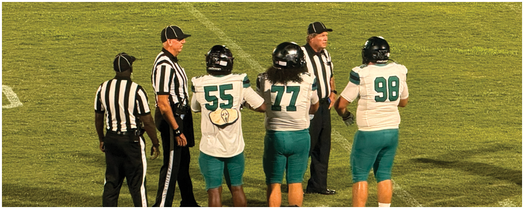 A group of men on a football field. Description generated by AI