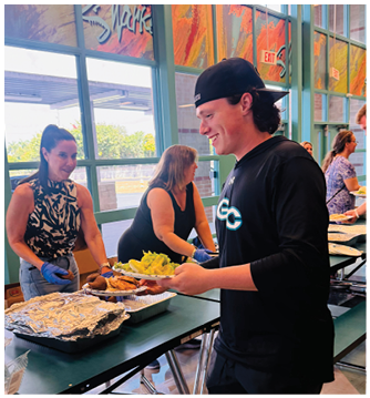 A man wearing a black shirt and black shorts is smiling. Description generated by AI