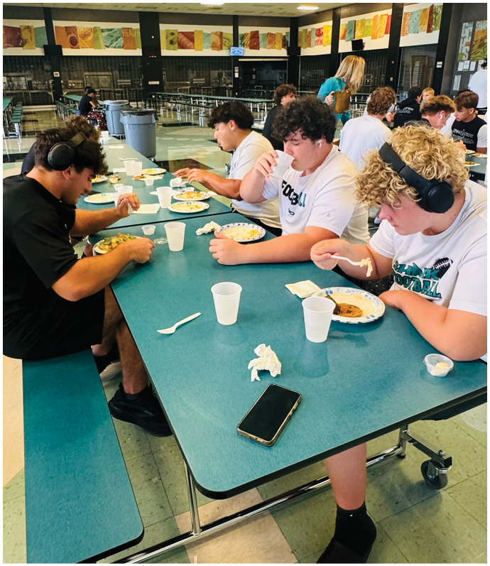 A group of people are sitting at a table eating. Description generated by AI