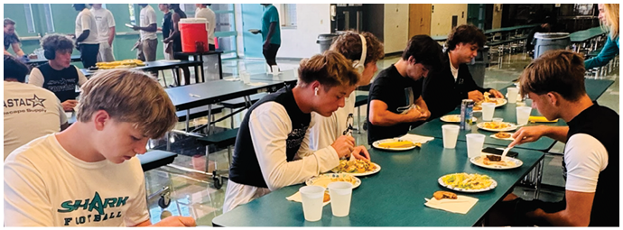 A group of people are sitting at a table eating. Description generated by AI