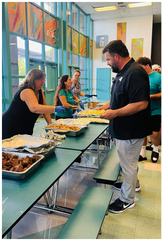 A man and a woman are serving food to people at a buffet. Description generated by AI