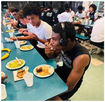 A group of people are sitting at a table eating. Description generated by AI