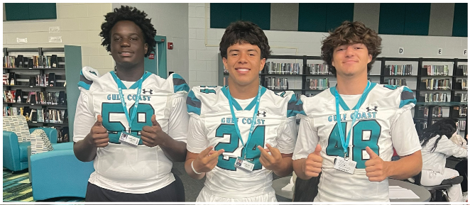 Three young men wearing football jerseys and shorts. Description generated by AI