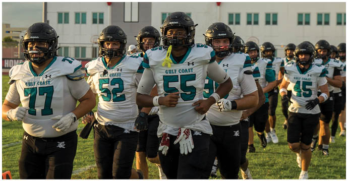 A group of football players running on the field. Description generated by AI