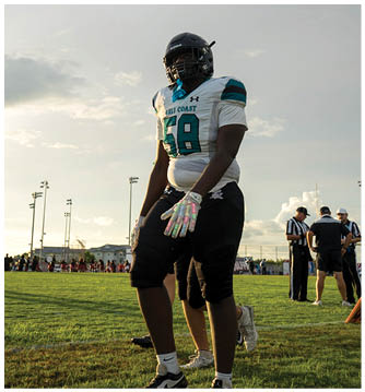 A man wearing a football uniform stands on a field. Description generated by AI