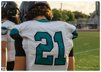 A football player wearing a white jersey with the number 21 on it. Description generated by AI