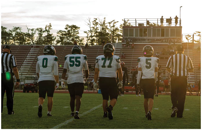 A group of football players standing on a field. Description generated by AI