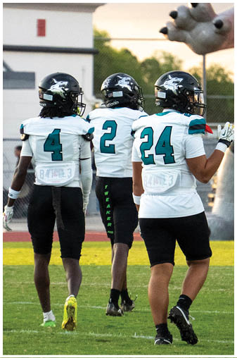 A group of football players walking on a field. Description generated by AI