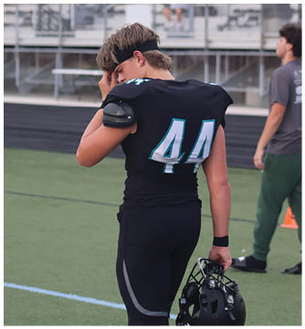 A football player wearing a black jersey with the number 44. Description generated by AI