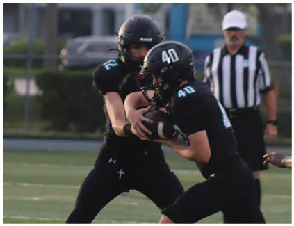 A football player in a black jersey is tackled by another player. Description generated by AI
