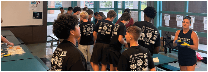A group of people wearing black shirts are standing in a room. Description generated by AI