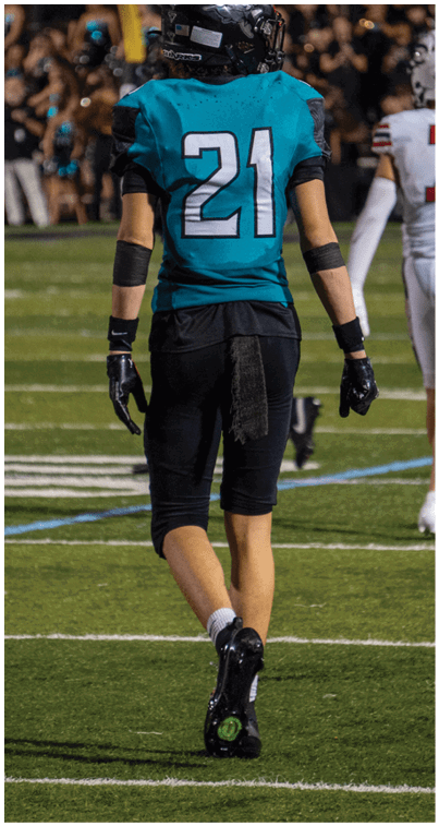 A football player wearing a blue and white uniform with the number 21 on the back. Description generated by AI