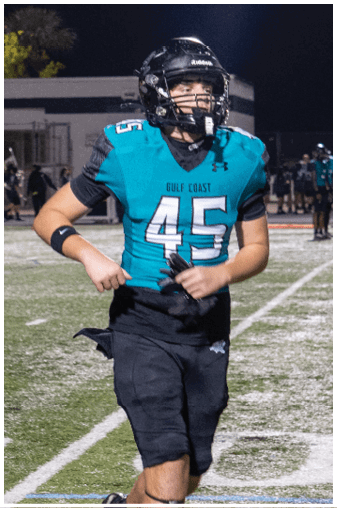 A football player in a blue and black uniform is running on the field. Description generated by AI