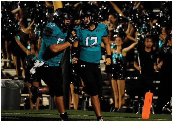 Two football players in blue and black uniforms talking to each other. Description generated by AI