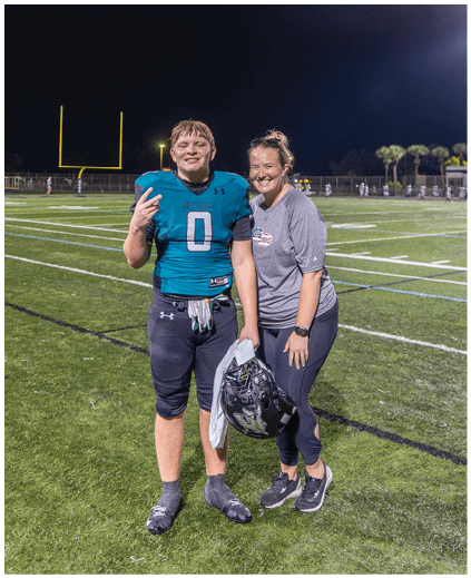 A football player and a cheerleader standing on a field. Description generated by AI