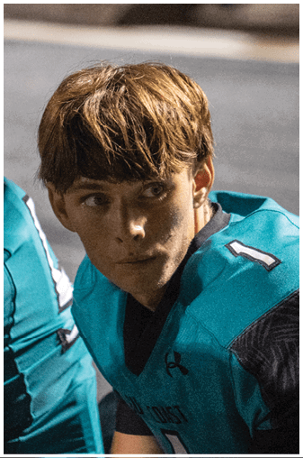 A young man wearing a blue football jersey. Description generated by AI