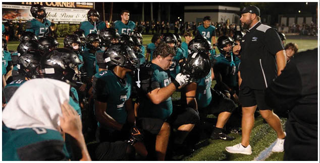 A group of football players wearing green and black uniforms. Description generated by AI