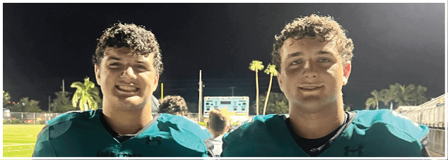 Two football players standing on a field. Description generated by AI