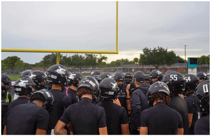 A group of football players wearing black helmets. Description generated by AI