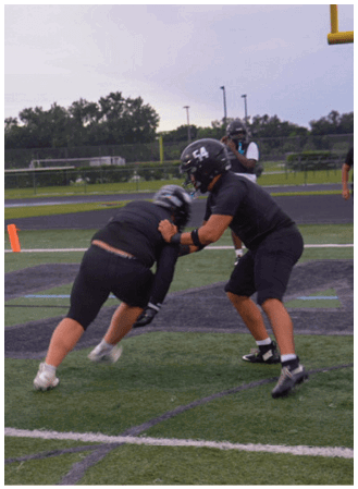 A football player in a black jersey is tackling another player. Description generated by AI