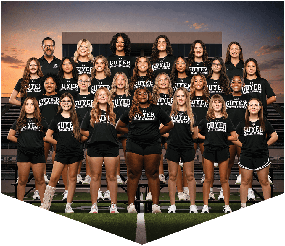 A group of people wearing matching black athletic training shirts pose together indoors in a tiered formation. Description generated by AI