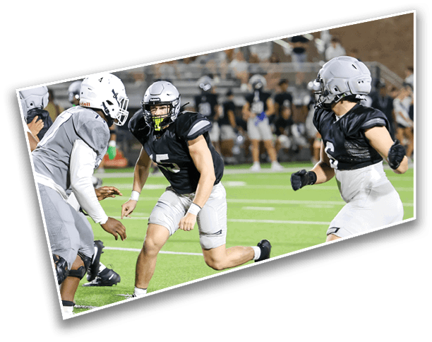 People wearing football uniforms are actively running and preparing to engage on a green field during a game. Description generated by AI