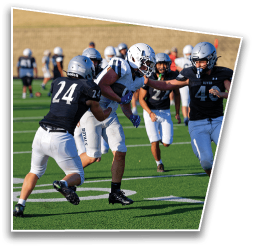 People wearing football uniforms are actively engaged in a game on a green field with white yard lines. Description generated by AI