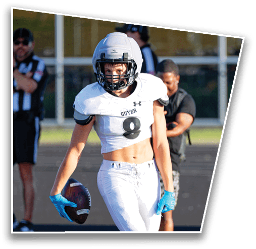 A person wearing a white football helmet and jersey with the number 8 and the word “GUYER" is on a football field with blurred officials in the background. Description generated by AI