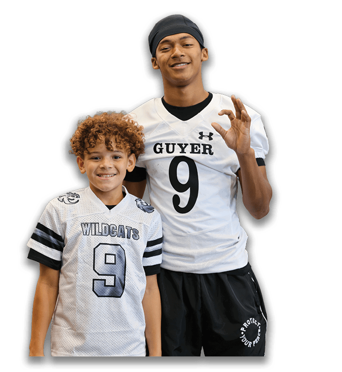 Two people wearing football jerseys with the number nine stand side by side, one making an okay hand gesture and both smiling. Description generated by AI