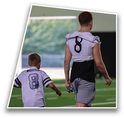 Two people wearing sports uniforms are standing with their backs to the camera, one with the number 8 visible on the shirt. Description generated by AI