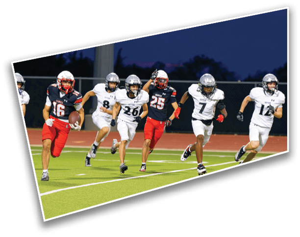 People wearing football uniforms are running on a field at night with one person holding a football. Description generated by AI
