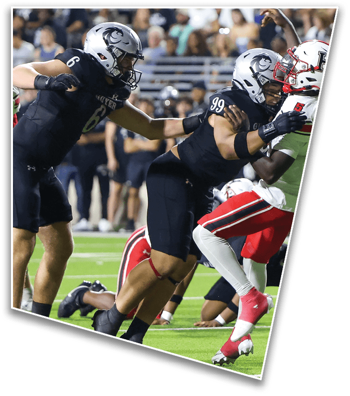 Two people in black football uniforms with silver helmets are tackling a person in a white and red football uniform on a green field during a game. Description generated by AI