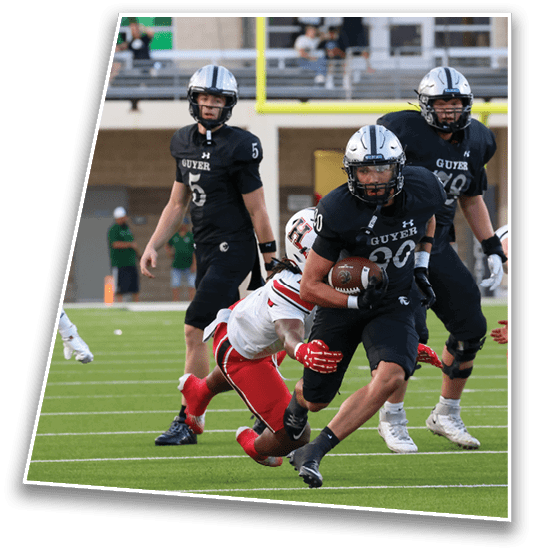 A person in a black football uniform is running with the ball while another person in a white and red uniform attempts to tackle them on a football field. Description generated by AI