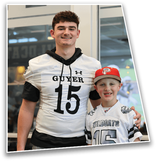 Two people wearing sports jerseys with the number 15 stand side by side indoors, one wearing a red cap and the other with a black hoodie under the jersey. Description generated by AI