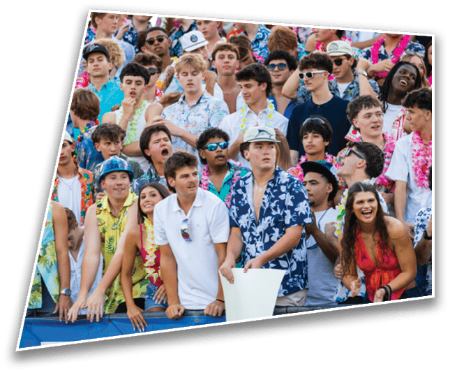 A large group of people wearing colorful Hawaiian shirts and leis are gathered closely together, some smiling and others looking excited or animated. Description generated by AI
