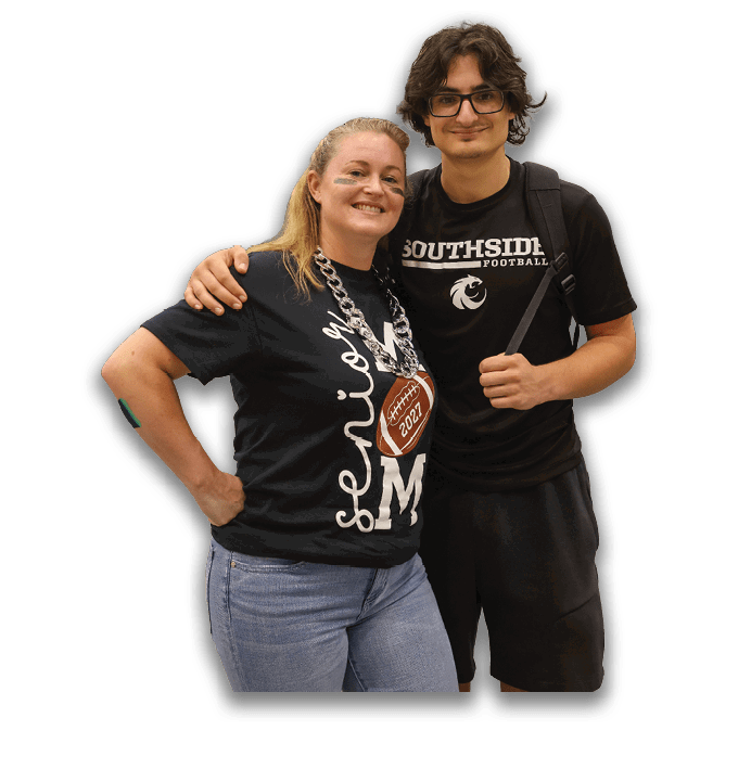 Two adults are smiling, one with glasses and medium-length wavy hair and the other with light-colored hair pulled back. Description generated by AI