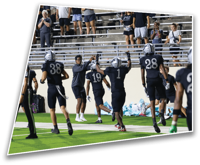 People in football uniforms are celebrating on a field near the stands while others in casual clothing watch and take photos. Description generated by AI